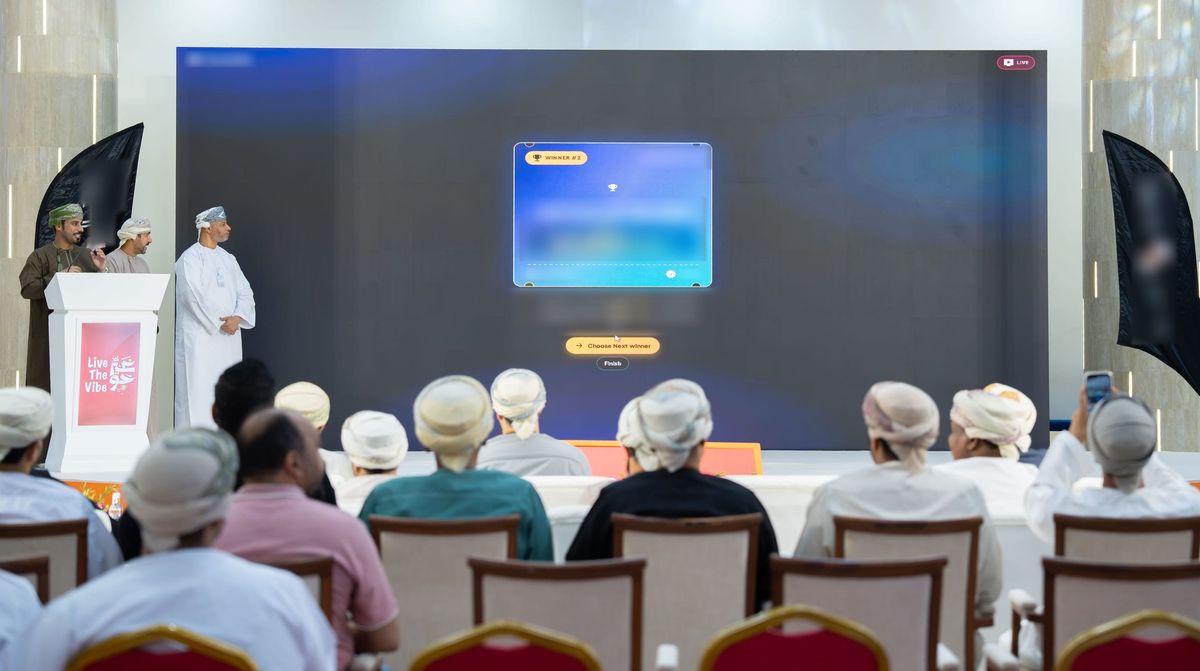 The live public draw run with eRaffle at the Live The Vibe award ceremony: the winner card on the big screen, presenters at the campaign podium, and the audience in the foreground. Winner details and sponsor branding are blurred.
