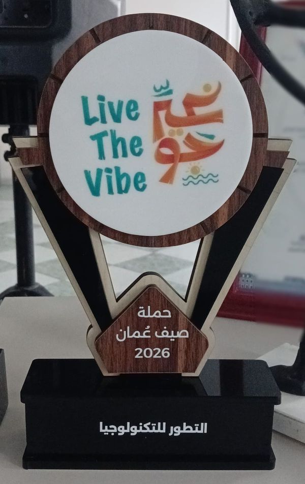 The Live The Vibe 2026 award: a wood-framed disc with the campaign’s artwork above a plaque, on a black base engraved with the company’s Arabic name.